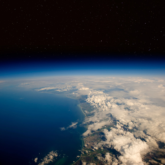 View of the upper atmosphere with ocean, land and clouds